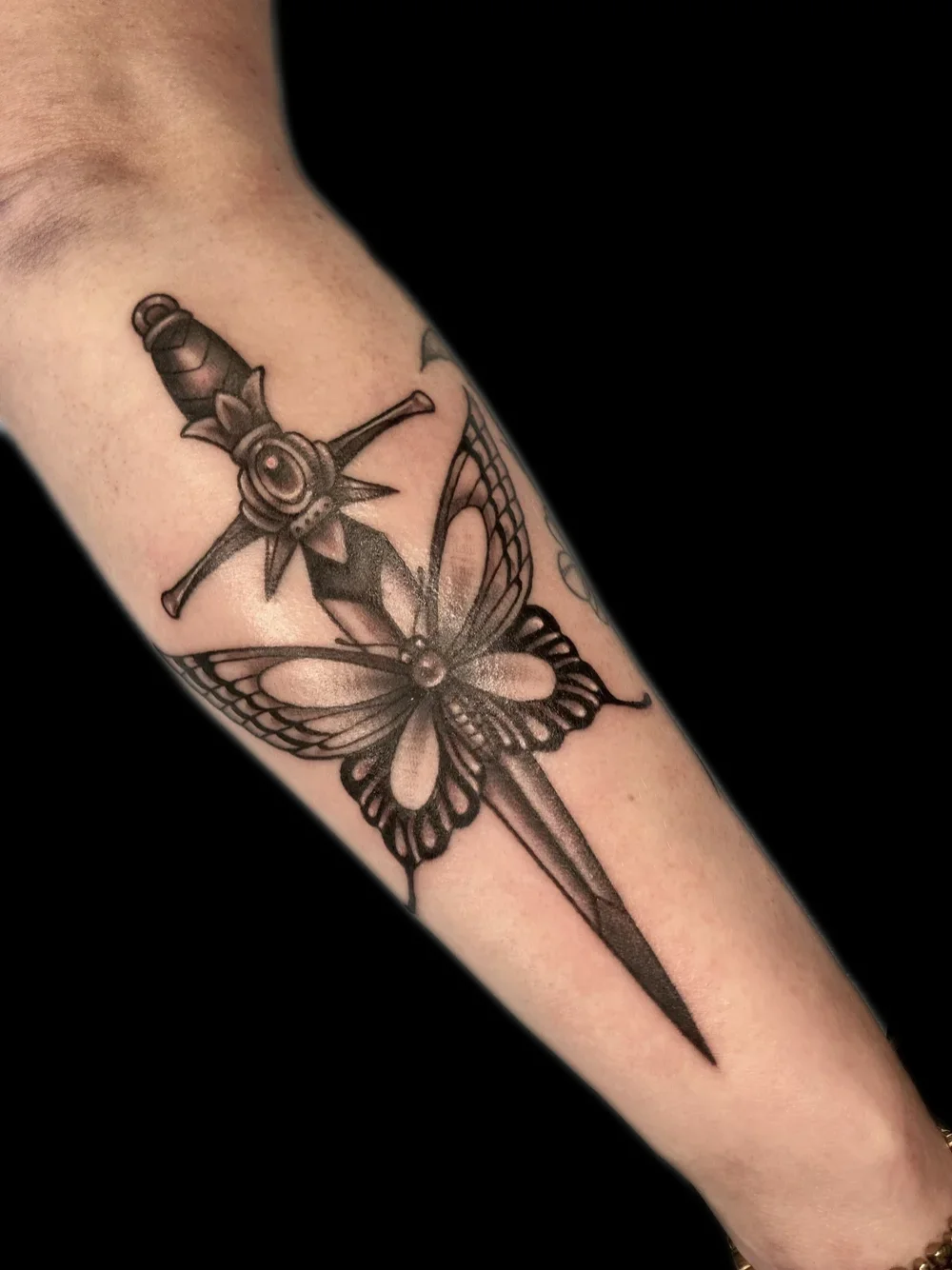 American traditional dagger through a butterfly tattoo, on the forearm