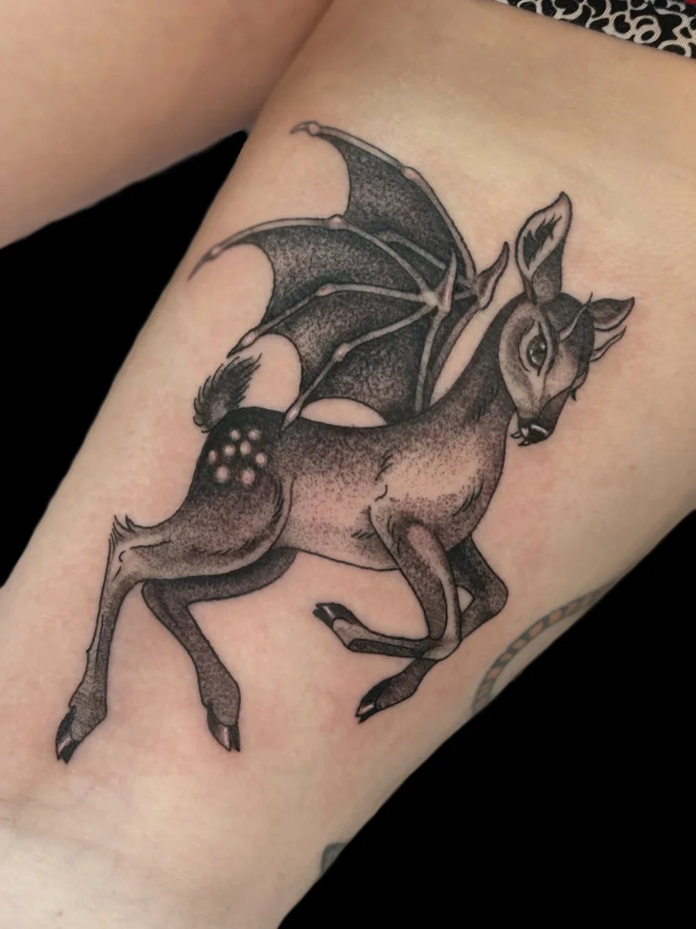 Dragon-deer chimera tattoo with bat-like wings, on the thigh