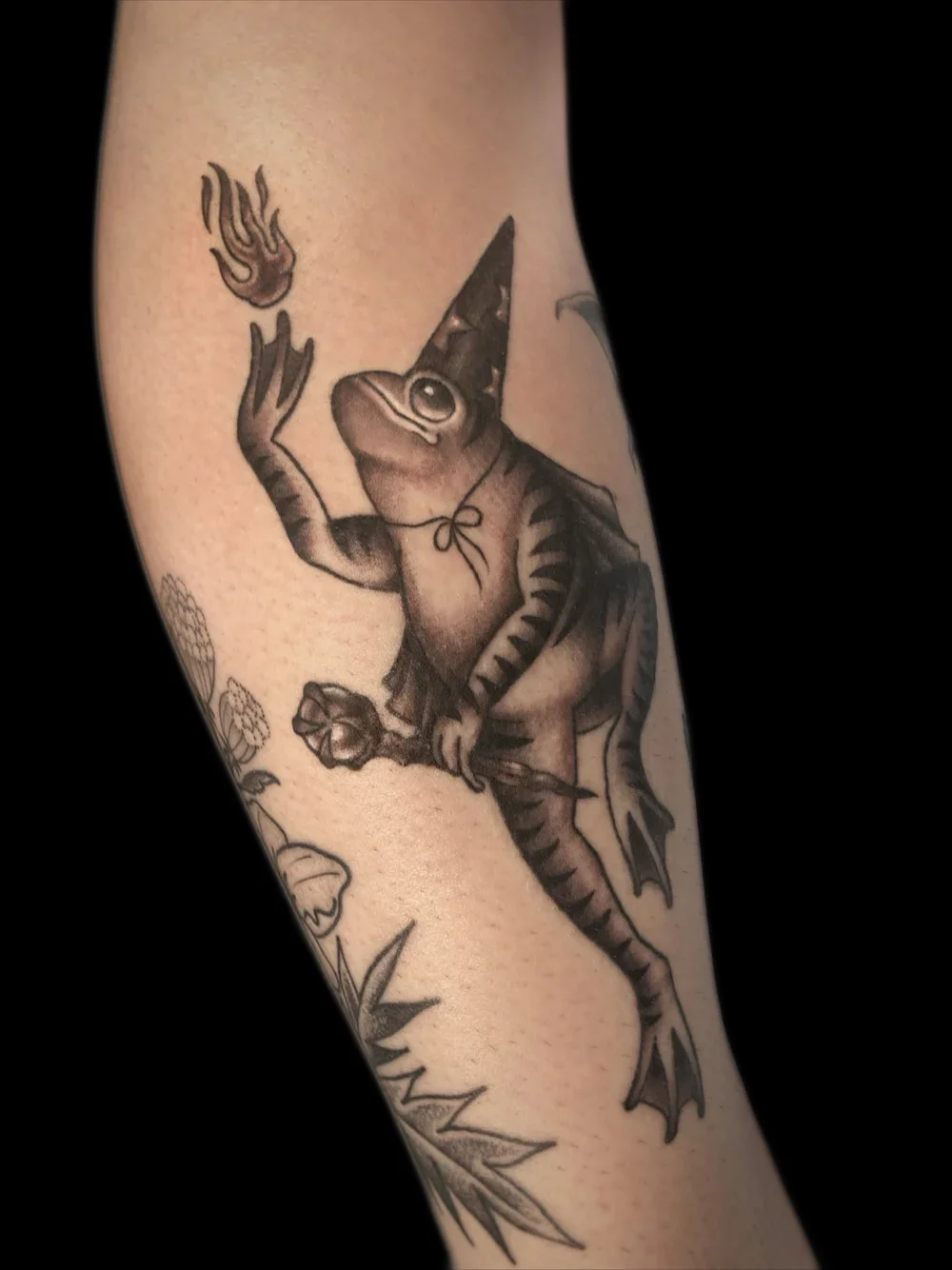 Wizard frog casting a fireball, tattoo on the forearm