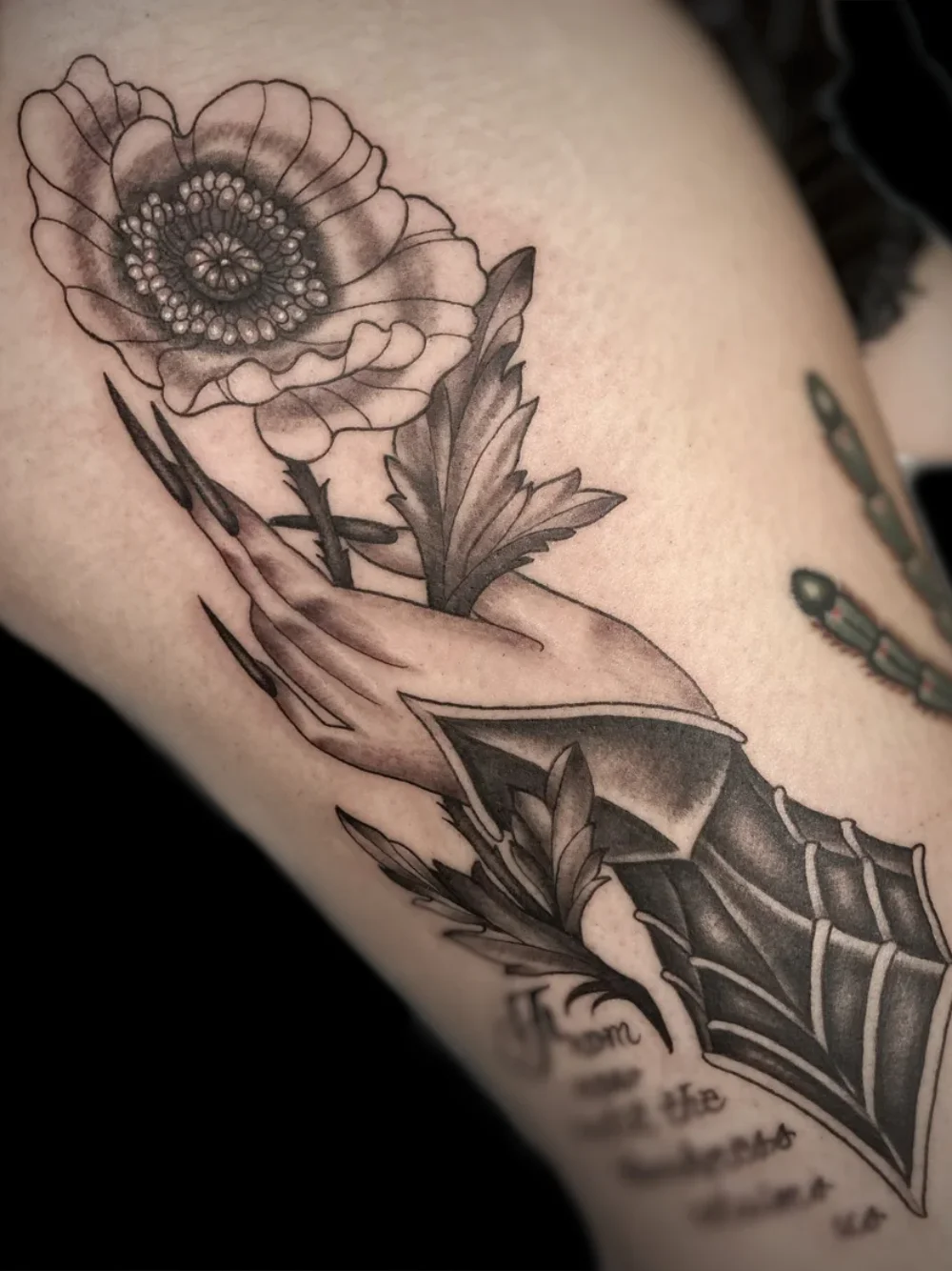 Victorian hand holding a poppy flower, tattoo on the back of the thigh